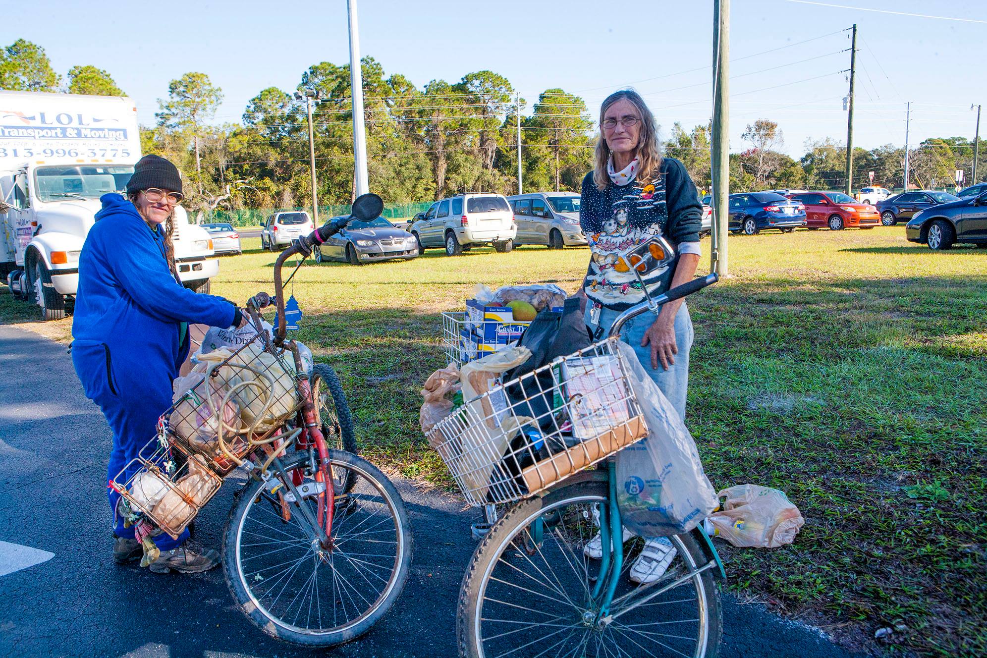 Sisters Cindy Powell, 58, and sixty-two-year old Janet Greil, R, rode their bikes for two hours to reach the 21st Annual Farm Share Holiday Food Giveaway at Faith Baptist Church in New Port Richey. Their car was repossessed and Cindy lost her job at a pig farm. They struggle to afford basic necessities. After waiting in line with the 600 other families, the two loaded a wagon with a cooler and rode the seven miles back on their tricycles. 